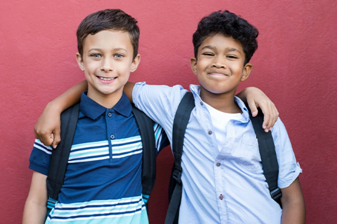 Dos jóvenes estudiantes sonriendo contra la pared de una escuela