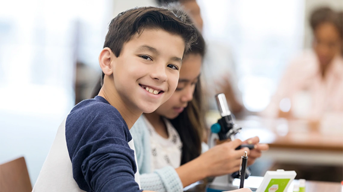 Estudiante en el aula sonriendo en el escritorio