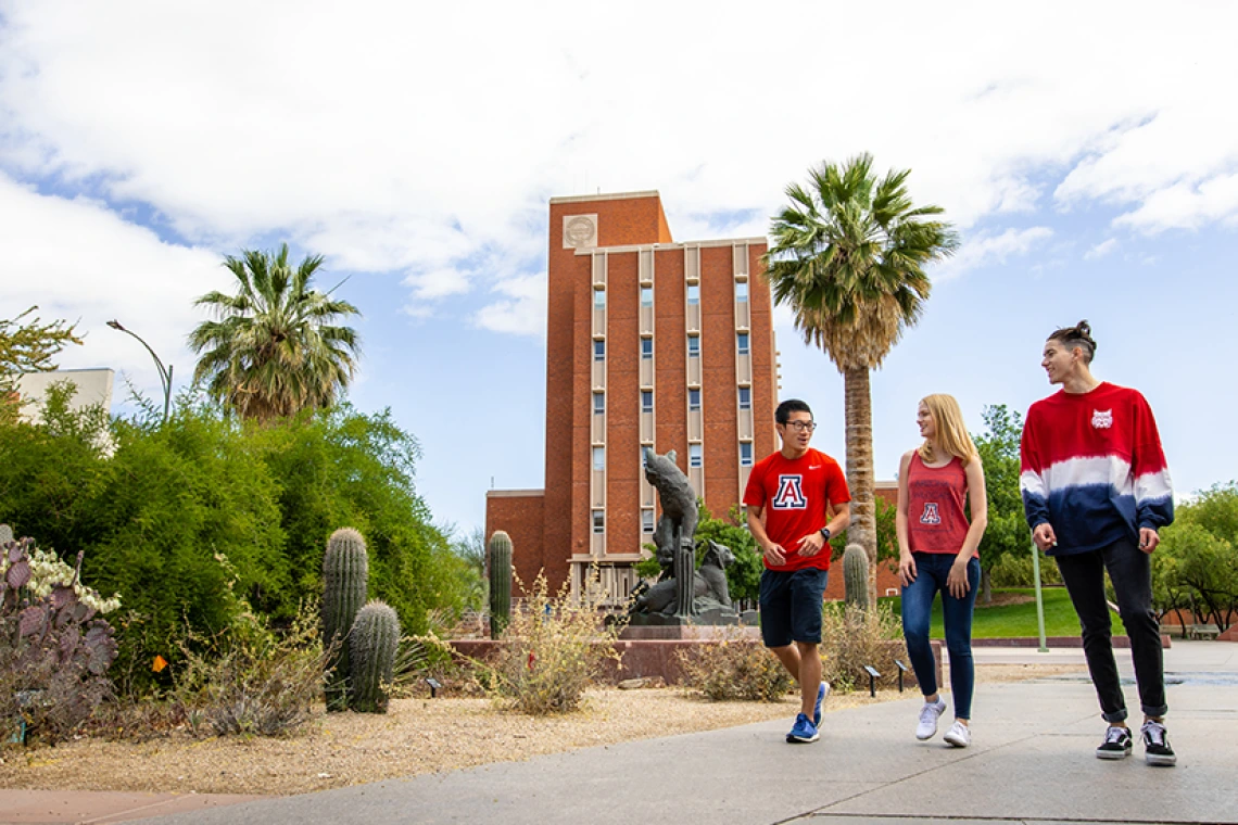 Tres estudiantes caminando juntos por el campus de la UA